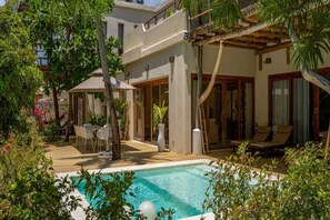 A pool area with a lounge chair, a table, and a covered seating area. - The Spice Island Grand Estate (Paje)