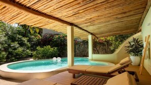 A covered outdoor area with a hot tub, lounge chairs, and a wooden deck. - Eco-Luxury Pool Villa (Paje)