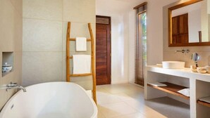 A modern bathroom with a freestanding bathtub, a wooden ladder, a large mirror, and a vanity with a sink. - Eco-Luxury Pool Villa (Paje)