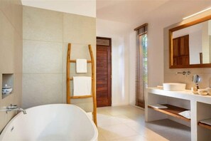 Ein modernes Badezimmer mit einer freistehenden Badewanne, einer Holzleiter, einem großen Spiegel und einem Waschtisch.