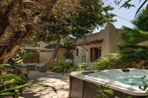 Ein Whirlpool in einem Garten mit einem Baum und einem Gebäude im Hintergrund.