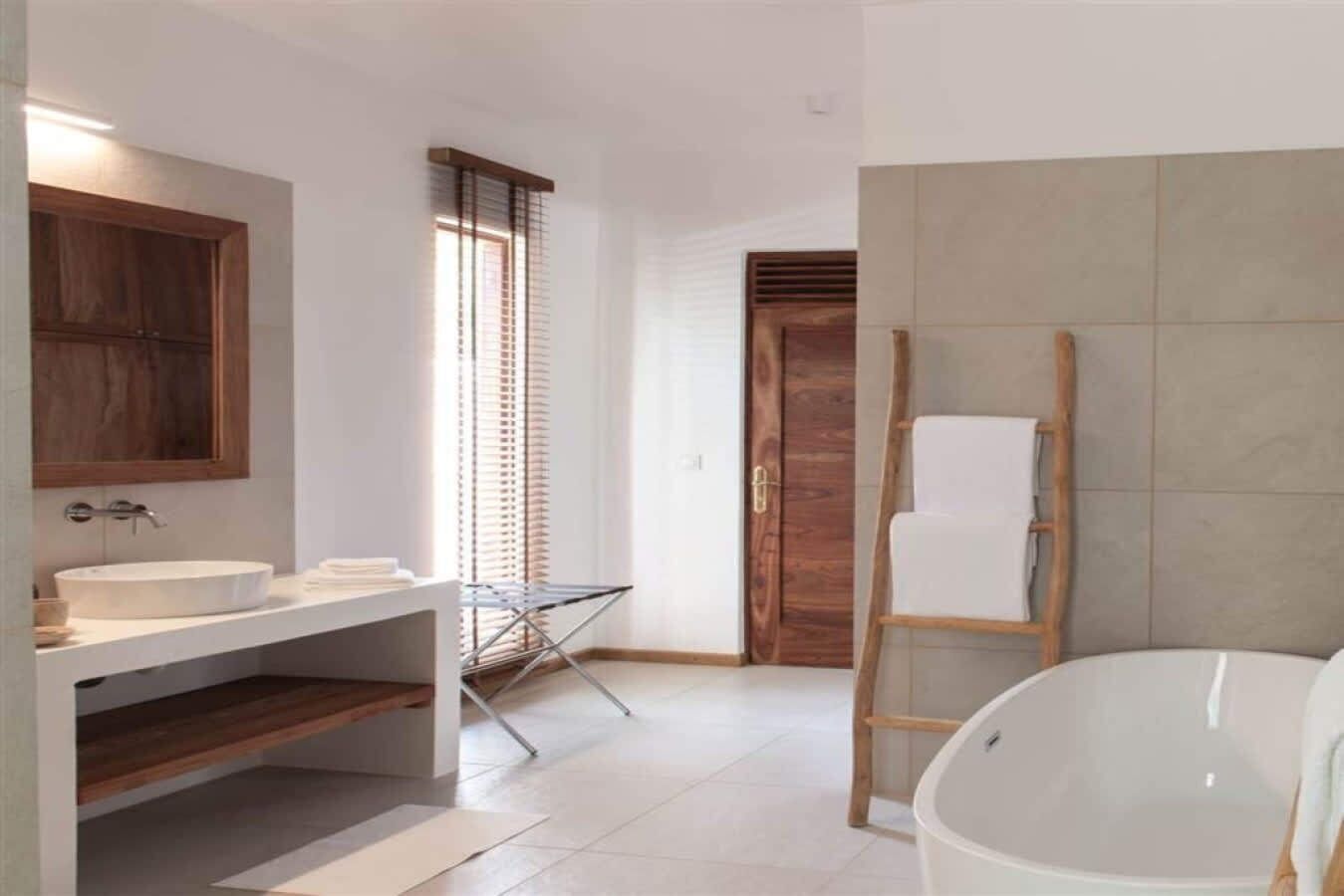 Ein modernes Badezimmer mit einer großen Badewanne, einem Waschbecken und einer Holztür.