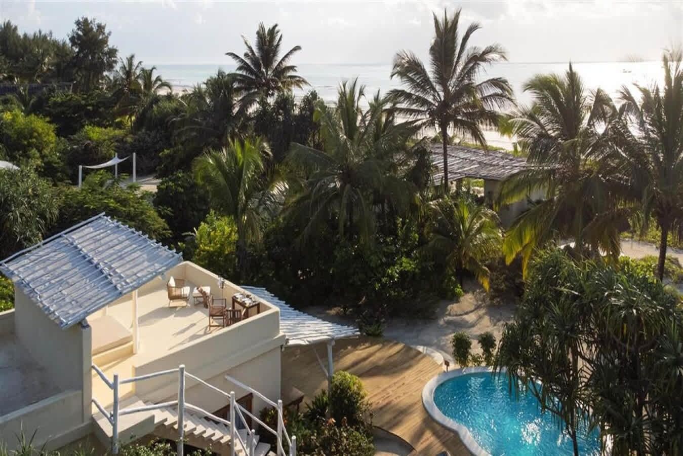 A resort with a pool, outdoor seating, and a view of the ocean.