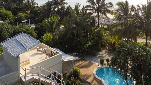 Un resort con piscina, area salotto esterna e vista sull'oceano.