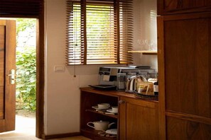 Eine Küchenzeile mit Holzschränken, einer Kaffeemaschine und einem Fenster mit Jalousien.