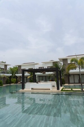 A modern hotel with a swimming pool, outdoor seating, and lush landscaping. - Pool Entry | 7 guests | 2 bedrooms (Monterrico)