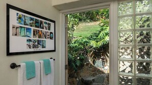 Uma colagem emoldurada de fotografias da natureza na parede, uma porta que dá para um jardim e uma janela com vista para uma parede de pedra.