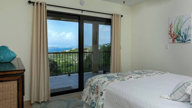 Quarto com uma cama, vista para uma varanda e um quadro na parede.