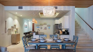 Un comedor con una mesa de madera dispuesta para cuatro personas, rodeado de sillas azules.