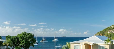 A coastal property with a house, a grassy area, and sailboats on the water.