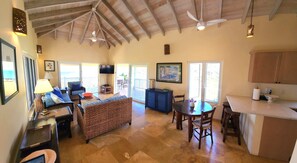 A spacious living area with a high ceiling, a dining table, and a kitchen area. - Elysium Villa-Natural Surroundings, Ocean Views, Private Pool! (Cruz Bay)