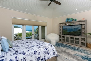 A bedroom with a bed, a television, and a balcony with outdoor furniture. - Nautilus-Beach Front, Family Friendly, Prime Locale (Cruz Bay)