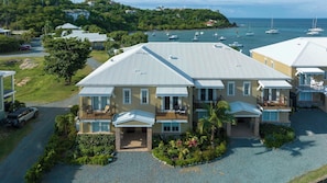A two-story house with a balcony, a driveway, and a view of the sea with boats. - Nautilus-Beach Front, Family Friendly, Prime Locale (Cruz Bay)
