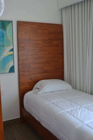 Un letto singolo con testiera in legno in una camera d'albergo.