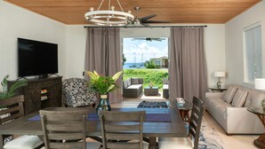 Ein modernes Wohnzimmer mit Essbereich, einem Fernseher und Blick auf das Meer.