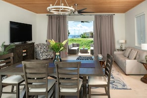 A modern living room with a dining area, a television, and a view of the sea. - Pirates Villa- Beach view with kayaks for Groups (Cruz Bay)