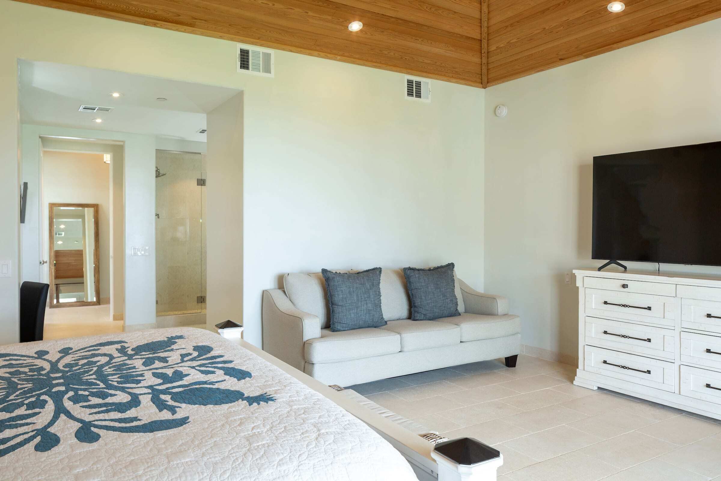 A bedroom with a bed, a sofa, a TV, and a dresser.