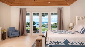 Ein Schlafzimmer mit Bett, einem Sessel, einer Lampe und Blick ins Freie.