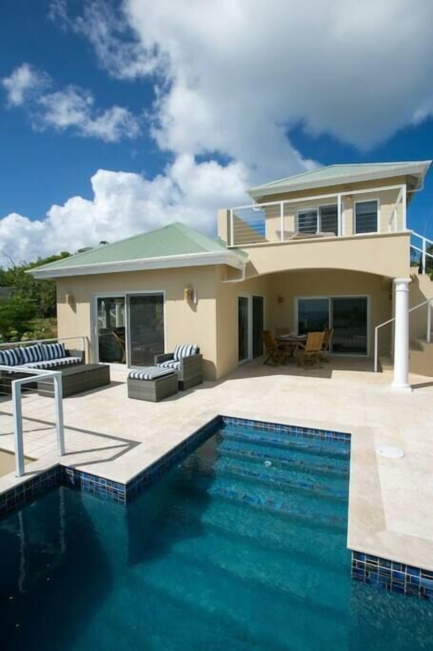 A two-story house with a swimming pool, outdoor seating, and a covered patio.