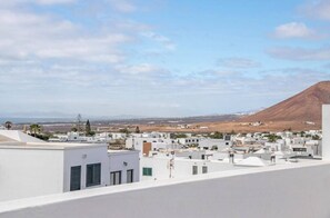 Eine Küstenstadt mit weißen Gebäuden, einem Berg im Hintergrund und blauem Himmel.