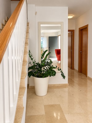 Ein Flur mit einer Treppe, einem Blumentopf, einem roten Stuhl und Holztüren.