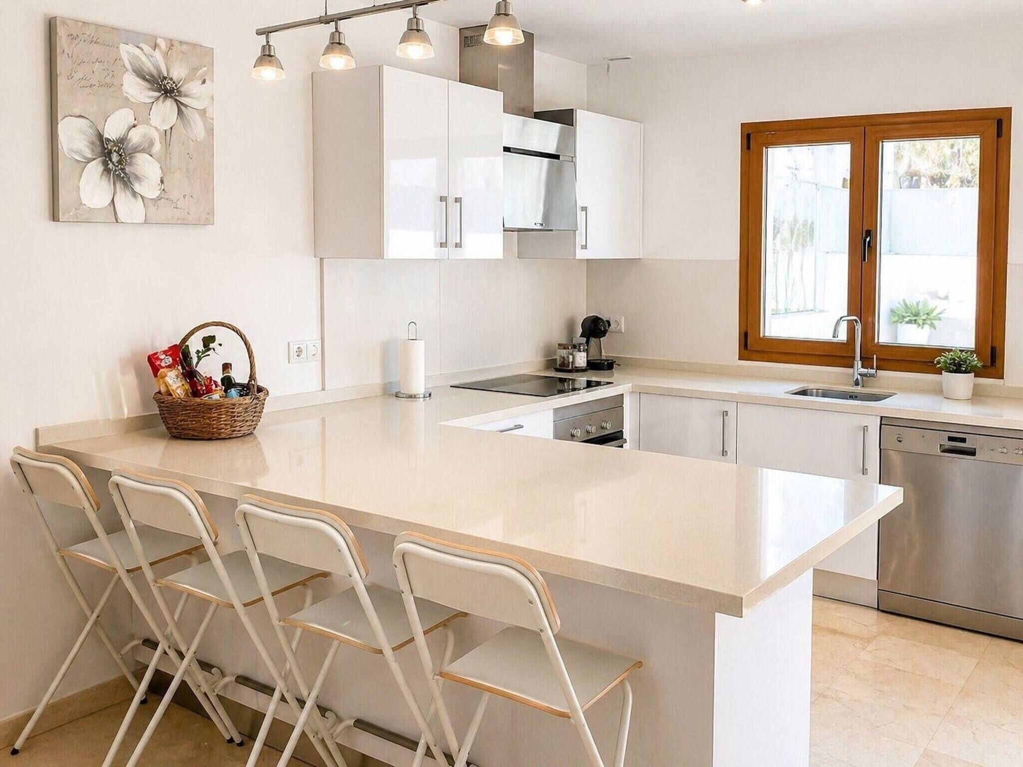 A modern kitchen with a central island, bar stools, a sink, and a dishwasher.