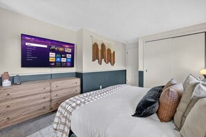 A hotel room with a bed, a dresser, a wall-mounted TV displaying a Roku TV interface, and a door. - Golf Course Oasis·Hot Tub·Family Fun·Club Pool (Galena)