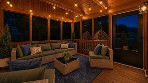Een overdekt terras met een houten dek, comfortabele zitmogelijkheden en sfeervolle lichtslingers.