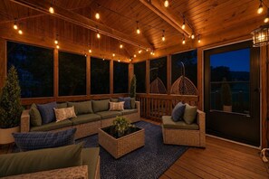 A covered outdoor seating area with a wooden deck, cushioned seating, and string lights. - Golf Course Oasis·Hot Tub·Family Fun·Club Pool (Galena)