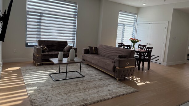 En rummelig stue med sofa, sofabord og spiseplads.