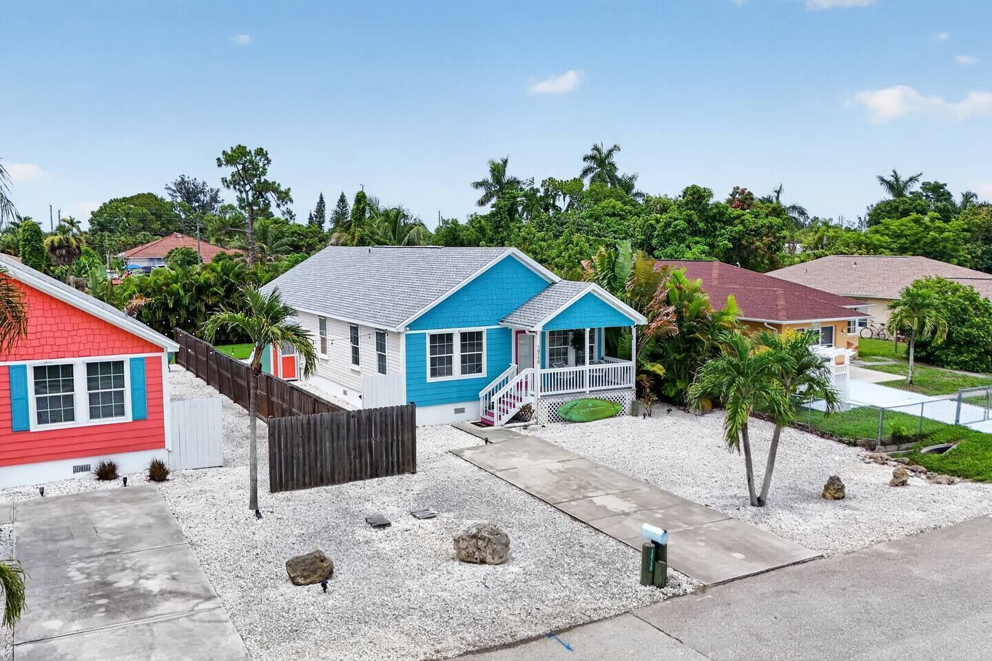 Un quartier résidentiel avec des maisons, une allée gravillonnée et un ciel dégagé.