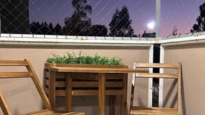 Una mesa de madera y dos sillas en un balcón con vista al cielo nocturno.