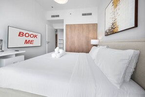 A hotel room with a bed, a desk with a chair, a TV, and a door leading to a bathroom. - Free Housekeeping Visits During Your Stay - Stayshort - Chic 1-bed for 4 in Prime Dubai Hills Location (Dubai)