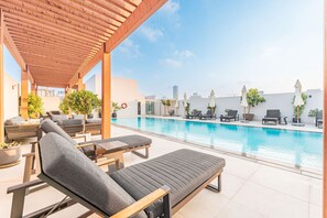 A rooftop pool area with lounge chairs, a pergola, and potted plants. - Free Housekeeping Visits During Your Stay - Stayshort - Contemporary 1 Bedroom Sleeps 4 in JVC (Dubai)