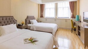 Een hotelkamer met twee bedden, een bureau en een raam met gordijnen.