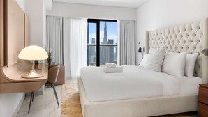 Ein modernes Hotelzimmer mit einem großen Bett, einem Schreibtisch mit Lampe und Blick auf die Stadt.