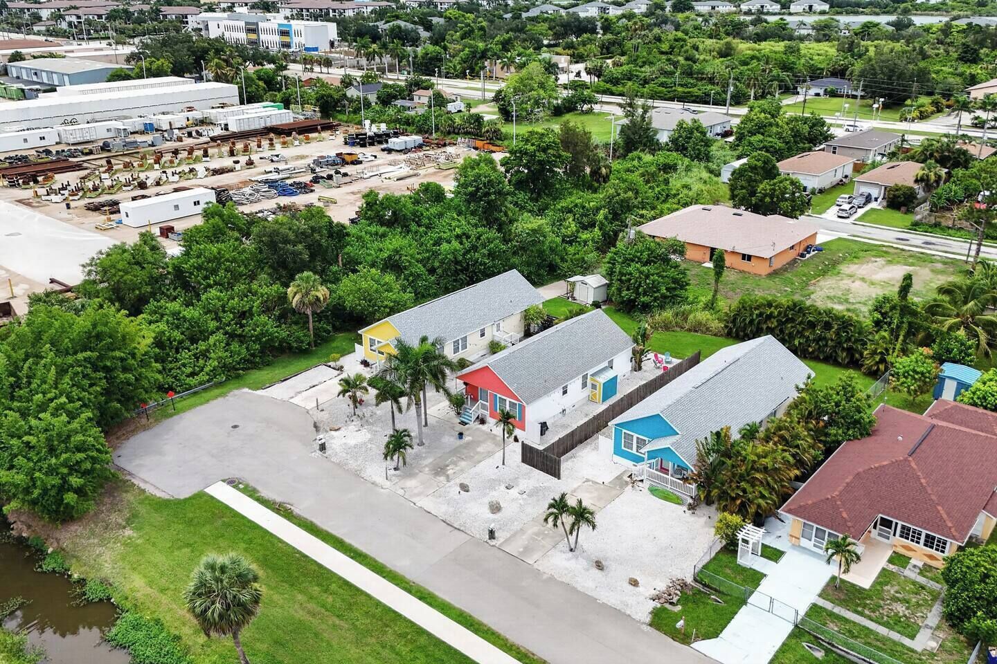 A residential area with houses, a parking lot, and a large industrial facility in the background.