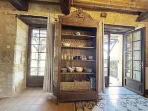 A room with a wooden cabinet containing dishes and a woven basket. There are two doors with glass panels and a window with curtains. - Marvelous 2-bedroom house with AC in charming Meyrals (Meyrals)