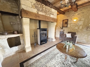A rustic interior with a stone fireplace, a sofa, and a wooden table. - Marvelous 2-bedroom house with AC in charming Meyrals (Meyrals)
