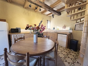 A kitchen with a wooden table, chairs, a microwave, and a sink. - Marvelous 2-bedroom house with AC in charming Meyrals (Meyrals)
