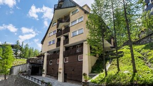 Ein mehrstöckiges Gebäude mit Balkonen, einer Steintreppe und umgebender Bepflanzung.