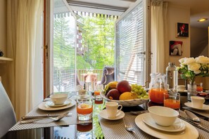 A breakfast table with a fruit bowl, a pitcher of orange juice, and a vase of white flowers. - The Ridge | Family Apartment with Matterhorn View (Breuil-Cervinia)