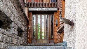 Eine Holztür mit der Aufschrift 'Le Pavillon' darüber, die zu einer Steintreppe führt.