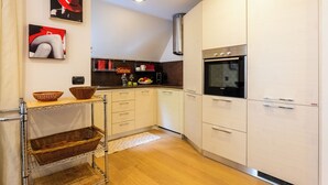 Eine moderne Küche mit weißen Schränken, einem eingebauten Backofen und einer hängenden Körbelement.