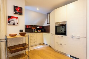 A modern kitchen with white cabinets, a built-in oven, and a hanging basket. - The Ridge | Family Apartment with Matterhorn View (Breuil-Cervinia)