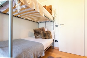 A bunk bed with a wooden frame, a white mattress, and a grey blanket.