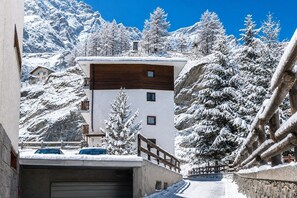 A mountain cabin with a wooden upper floor and a white lower floor, surrounded by snow-covered trees and mountains. - Cretaz Nest - Central Studio near Ski Lifts (Breuil-Cervinia)