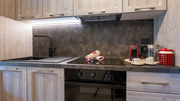 A kitchen with a black countertop, a sink, a stove, and a coffee maker. - Cretaz Nest - Central Studio near Ski Lifts (Breuil-Cervinia)