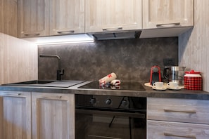 A kitchen with a black countertop, a sink, a stove, and a coffee maker. - Cretaz Nest - Central Studio near Ski Lifts (Breuil-Cervinia)