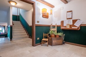 A staircase leading to a landing with a wooden chair and potted plants. - Cretaz Nest - Central Studio near Ski Lifts (Breuil-Cervinia)